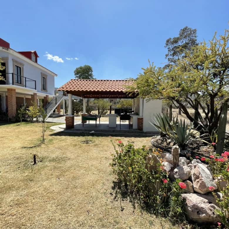 Outdoor garden with seating area, trees, and colorful flowers in a residential property.
