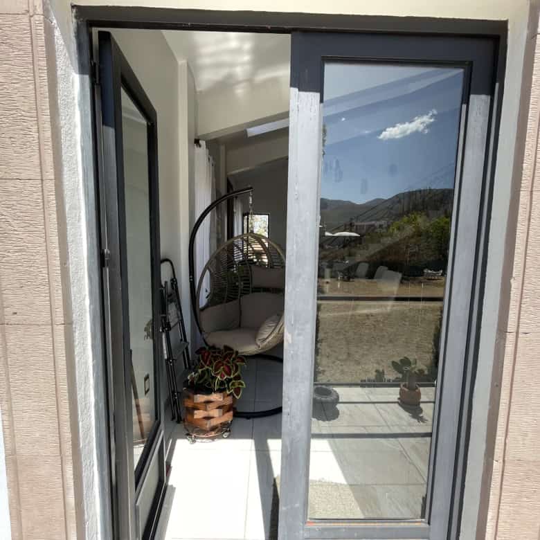Modern glass door leading to a balcony with mountain scenery.
