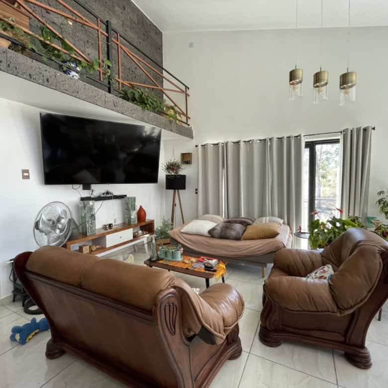 Spacious living room with leather sofas, large TV, and high ceilings.