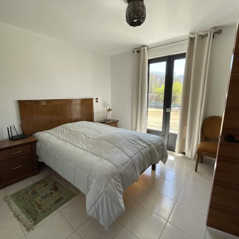 Bright bedroom with large window and neutral tones, perfect for relaxing and enjoying natural light.