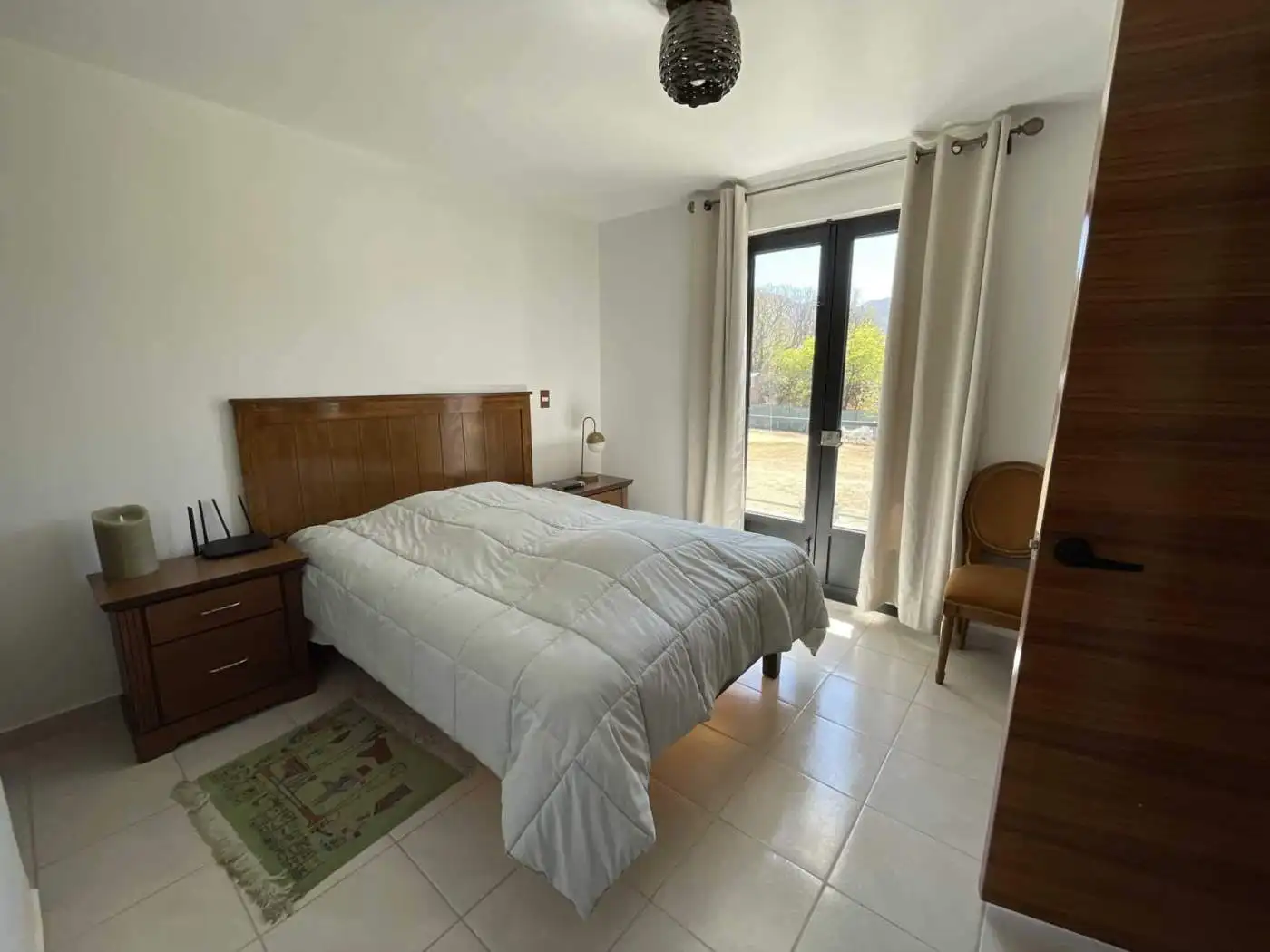 Bright bedroom with large window and neutral tones, perfect for relaxing and enjoying natural light.