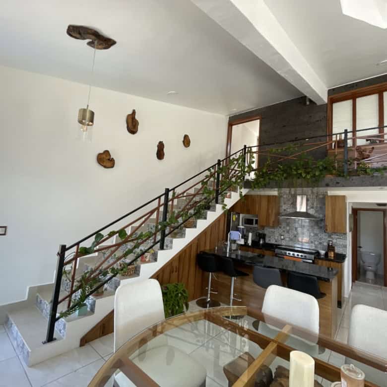 Modern open-plan living space with staircase and kitchen area, featuring stylish decor and natural l.