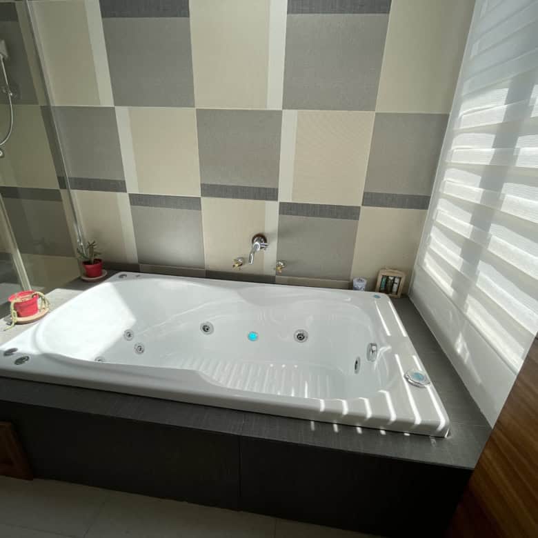 Modern bathroom with a spacious Jacuzzi tub and stylish tiled walls.