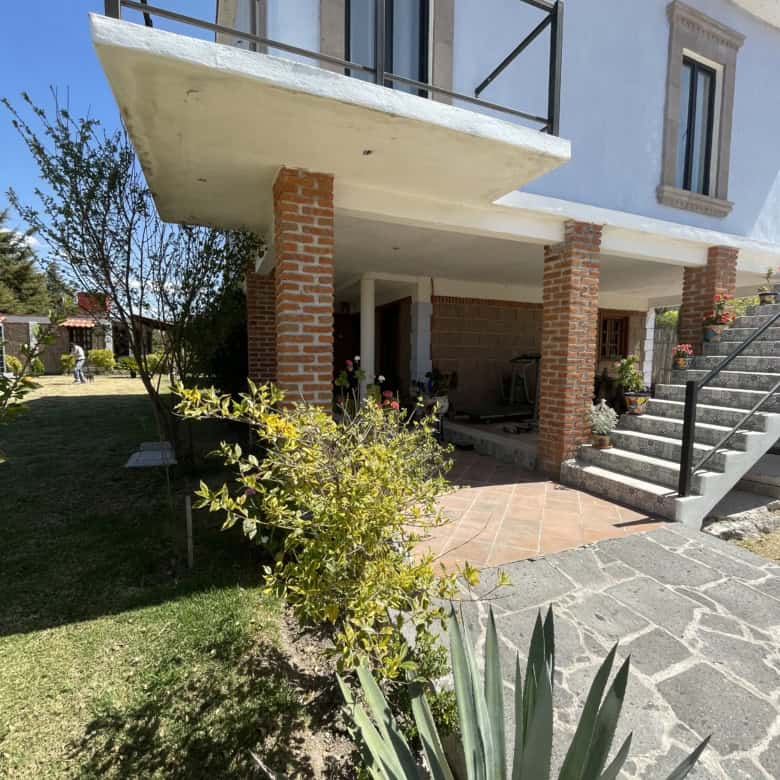 Stylish two-story home featuring a spacious balcony, brick accents, and lush garden surroundings.