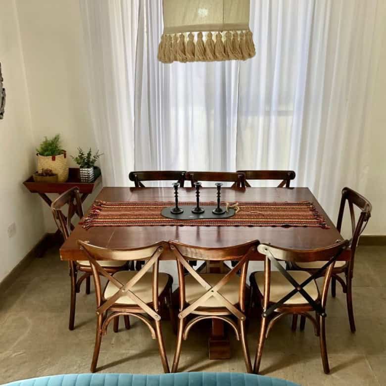 Elegant dining room with wooden table, chairs, and natural light.