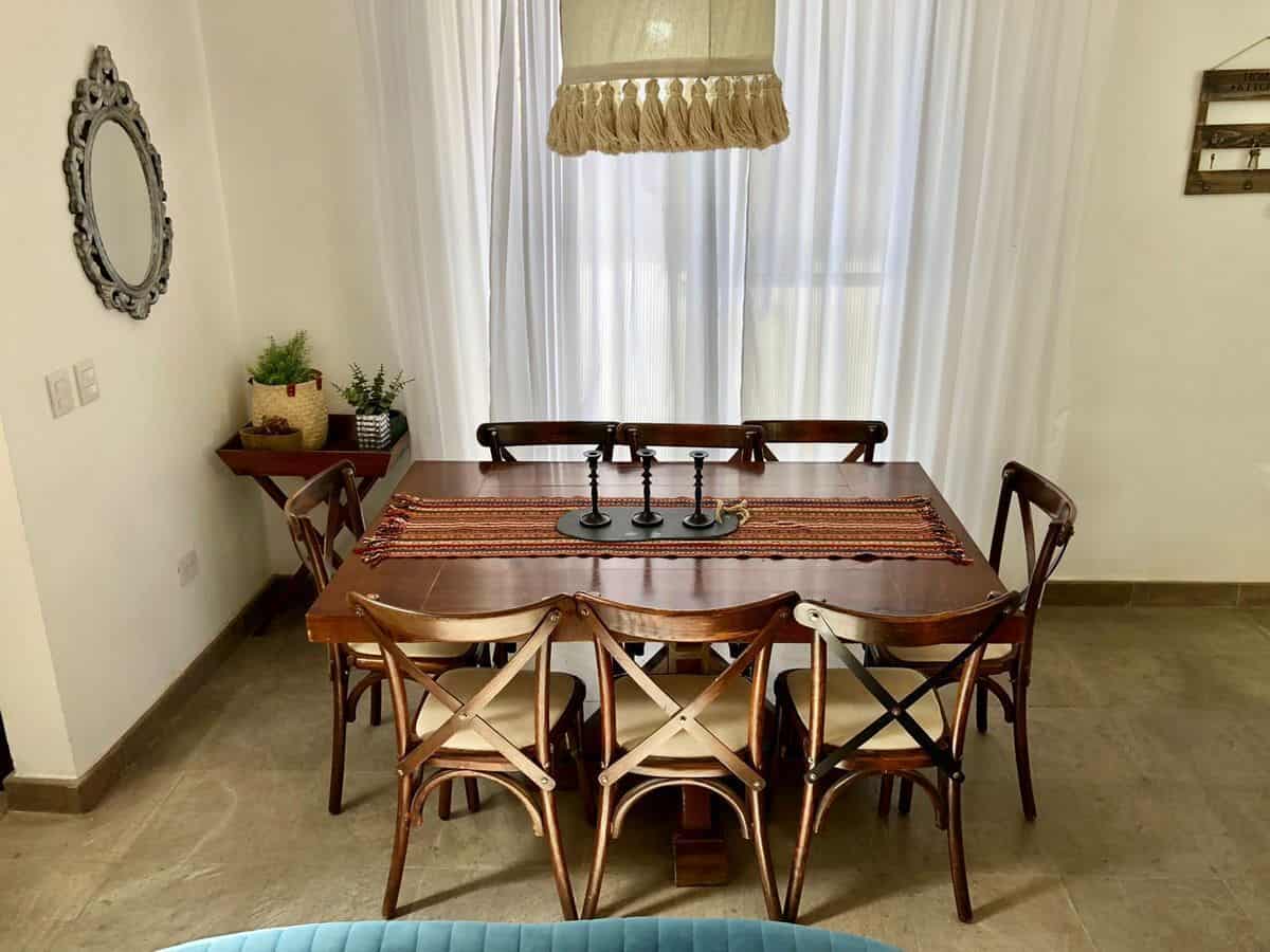 Elegant dining room with wooden table, chairs, and natural light.