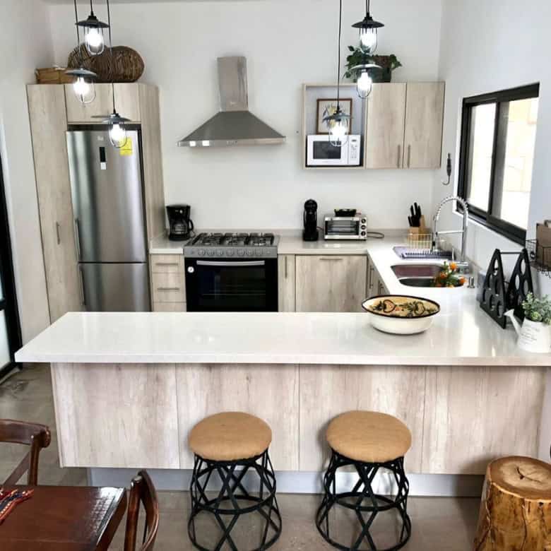 Modern kitchen with white cabinets, stainless steel appliances, and a breakfast bar.