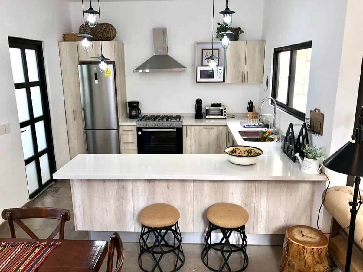 Modern kitchen with white cabinets, stainless steel appliances, and a breakfast bar.