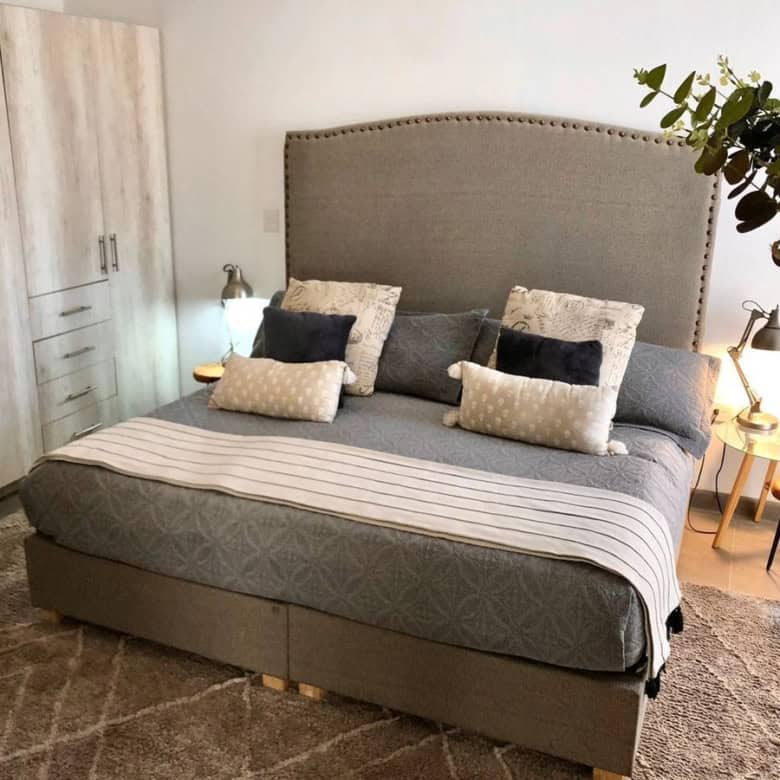 Modern bedroom with large bed, neutral decor, and built-in wardrobe for storage.