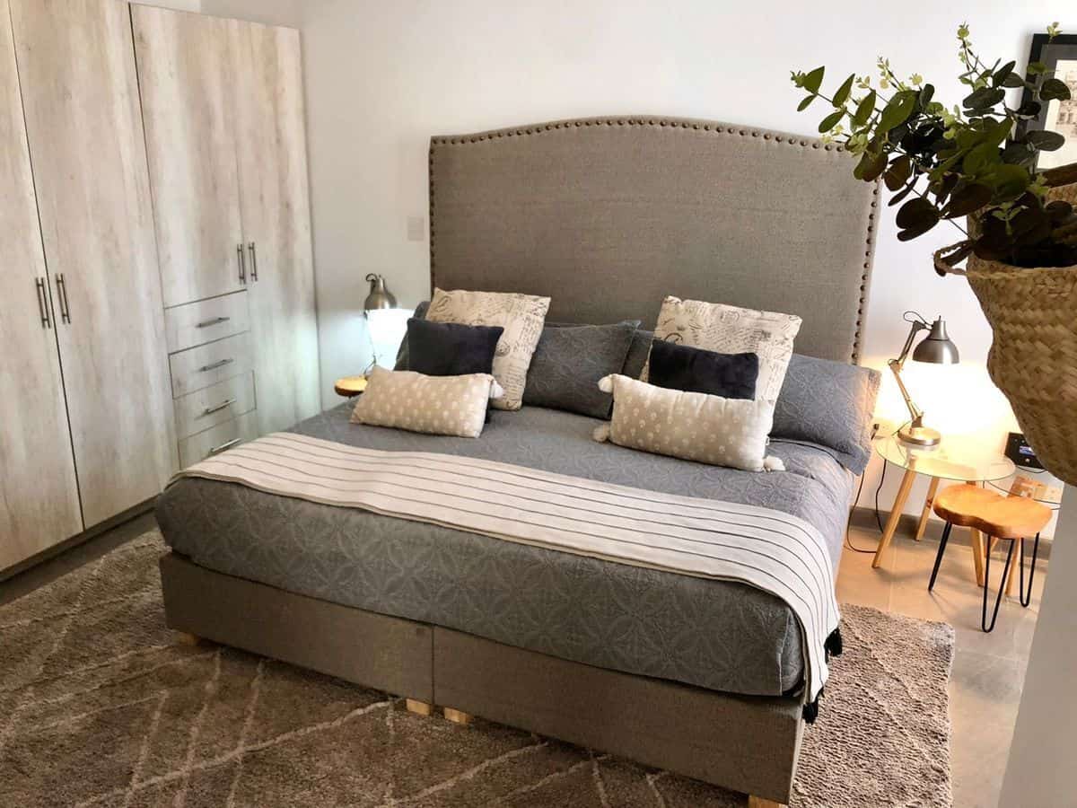 Modern bedroom with large bed, neutral decor, and built-in wardrobe for storage.