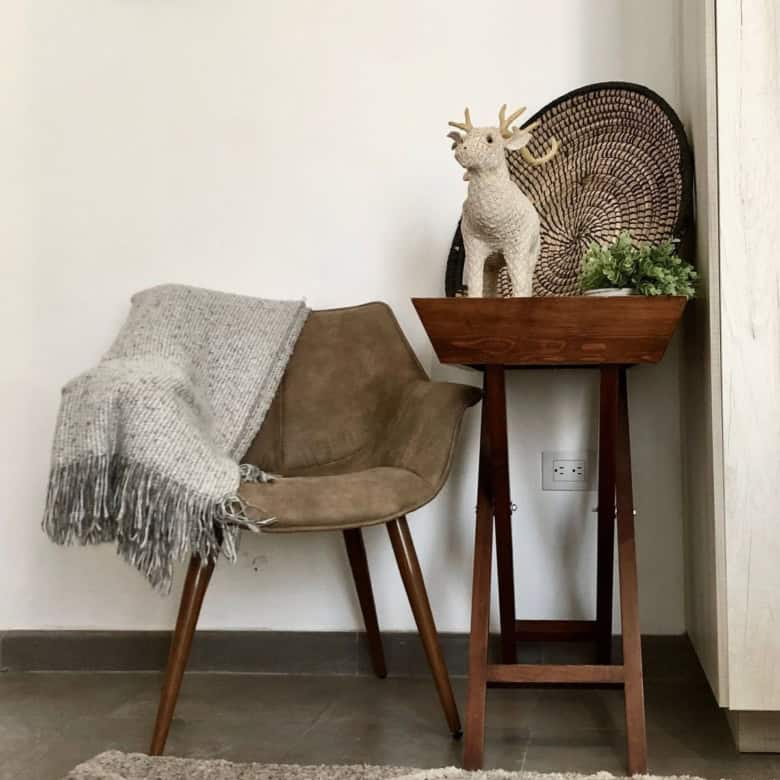 Stylish interior with cozy chair, decorative reindeer, and plant on wooden stand.