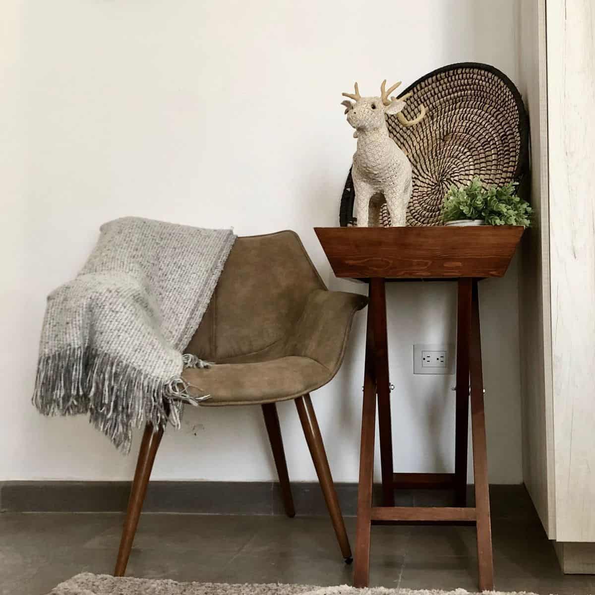 Stylish interior with cozy chair, decorative reindeer, and plant on wooden stand.