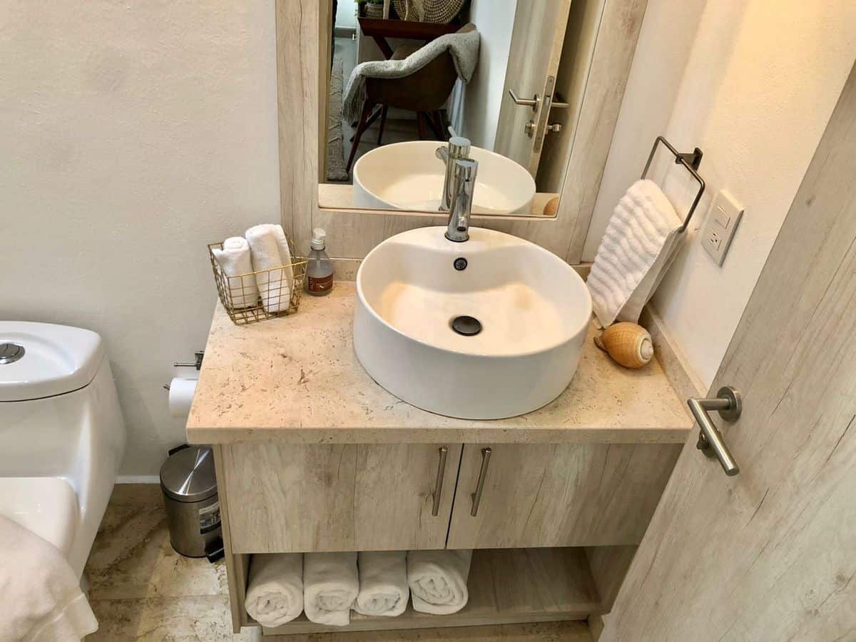 Modern bathroom with round vessel sink and wooden vanity for stylish home decor.