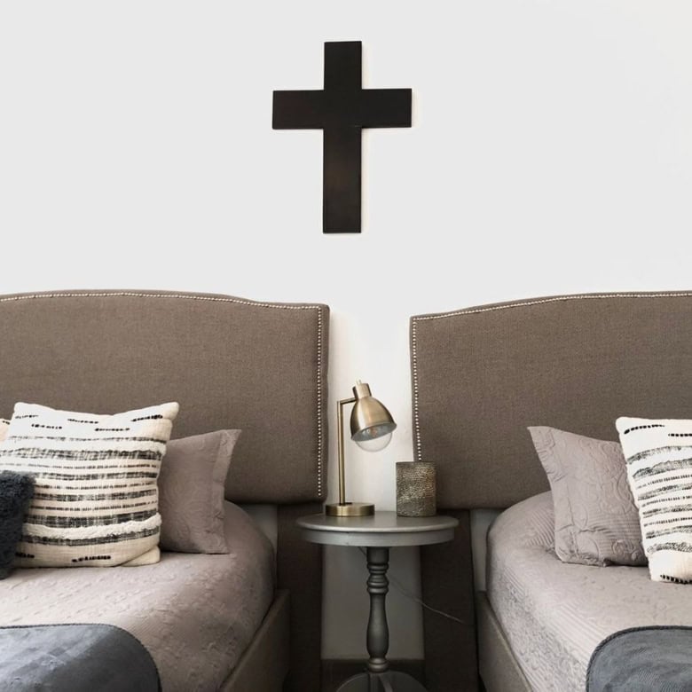 Modern bedroom with cross wall art above beds and cozy pillows.