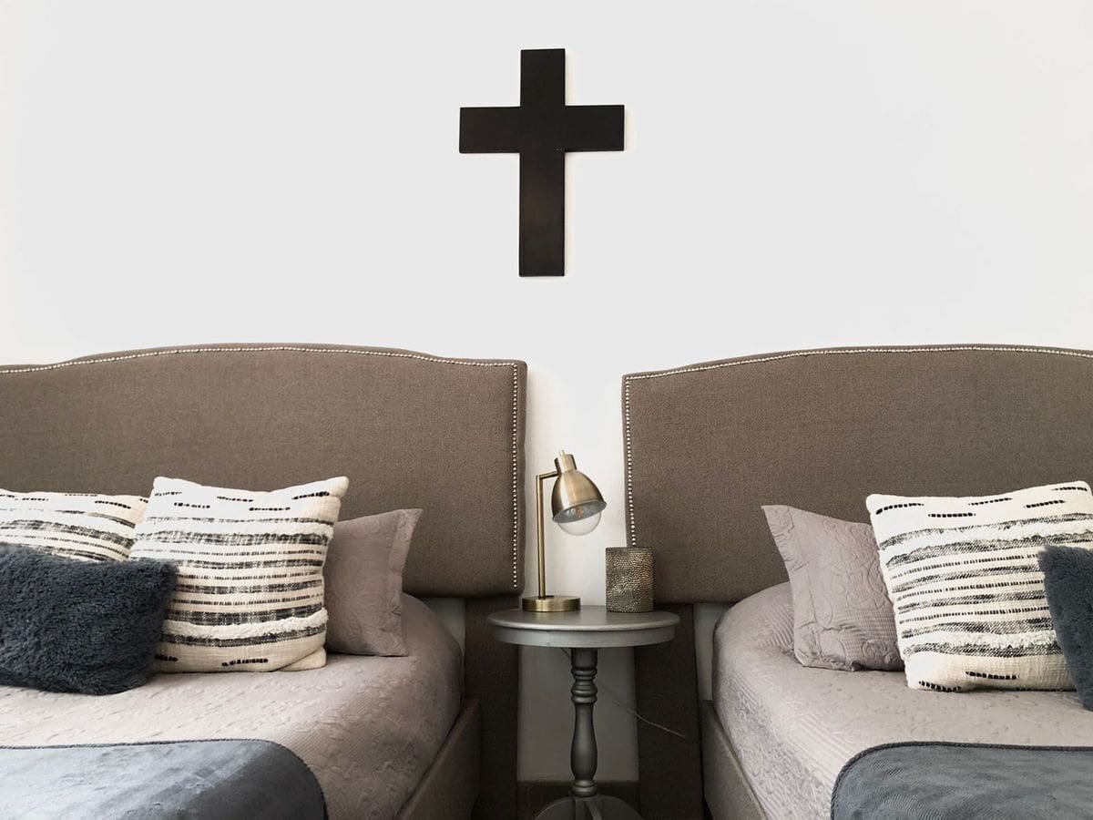 Modern bedroom with cross wall art above beds and cozy pillows.
