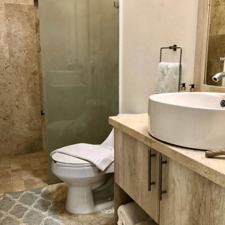 Modern bathroom with beige tiles and a glass shower enclosure.