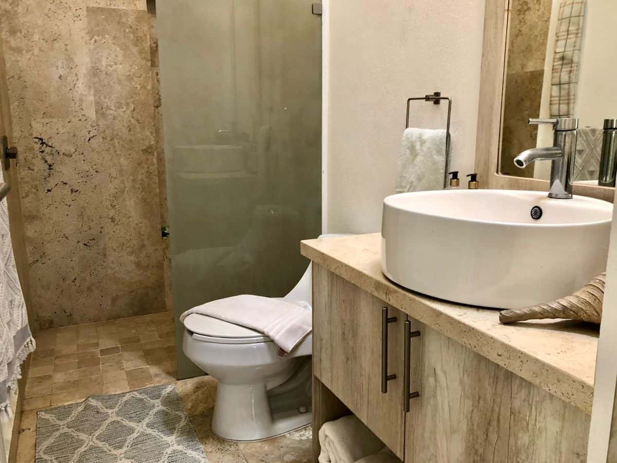 Modern bathroom with beige tiles and a glass shower enclosure.