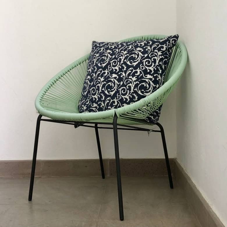 Modern green chair with decorative cushion for stylish interior decor.