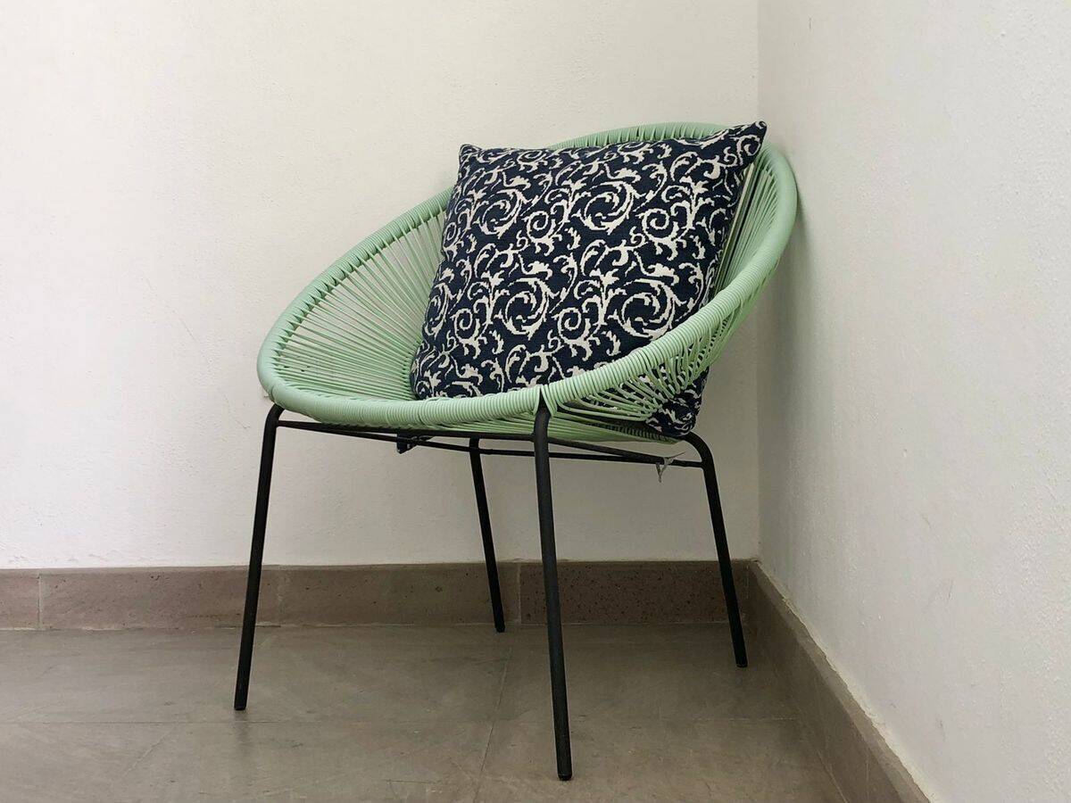 Modern green chair with decorative cushion for stylish interior decor.