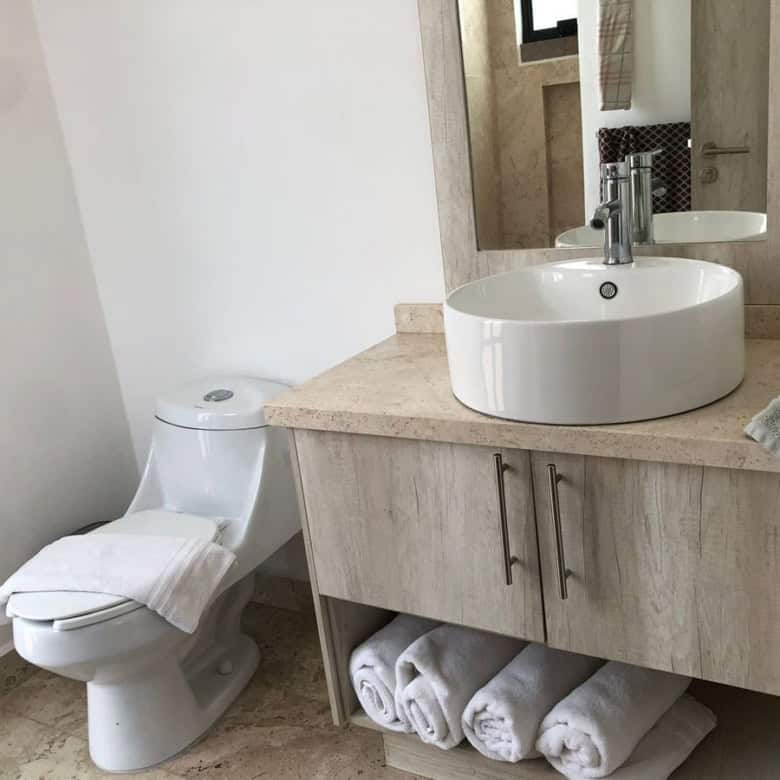 Modern bathroom with white toilet and vanity sink for sale.