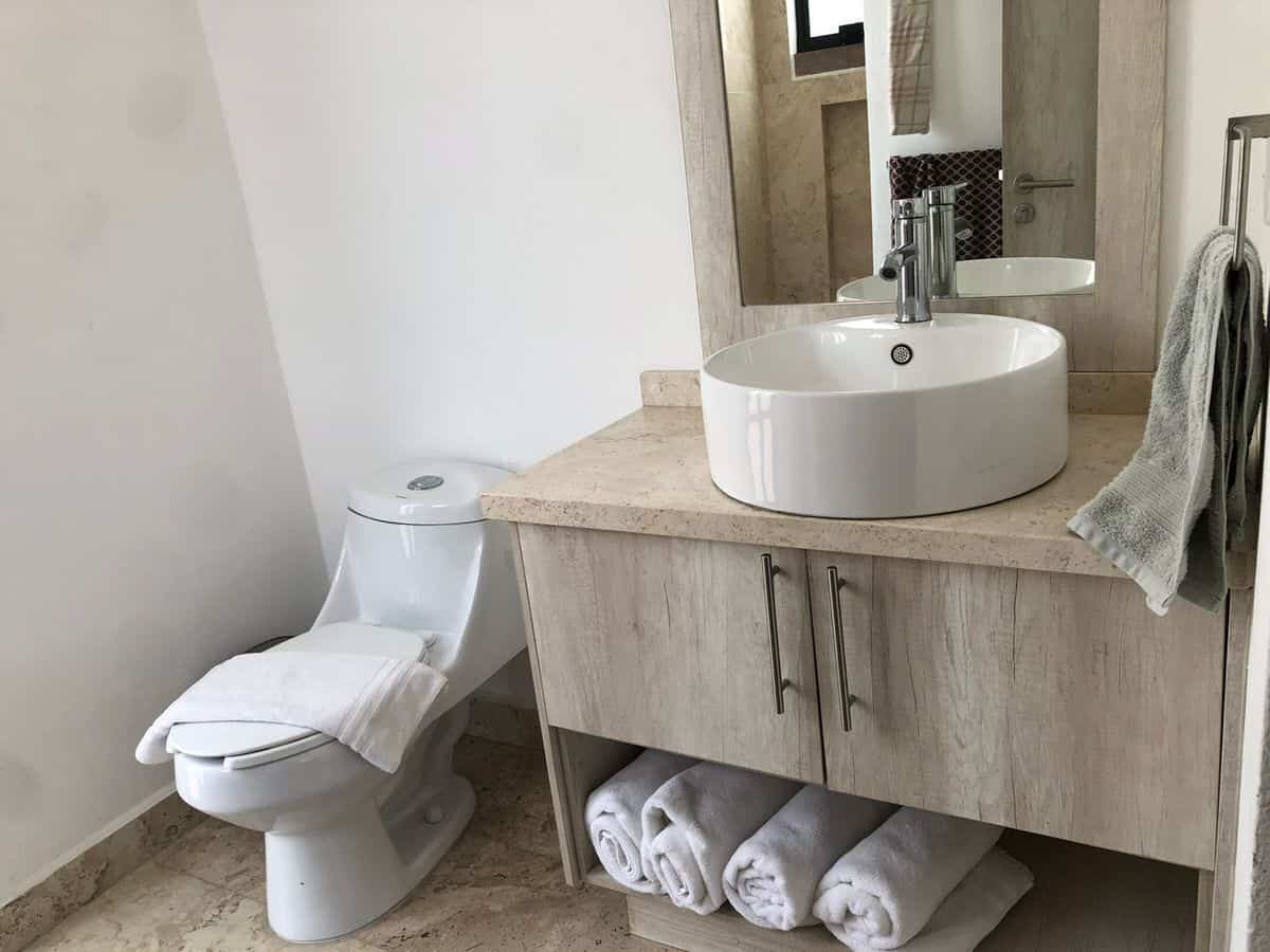Modern bathroom with white toilet and vanity sink for sale.