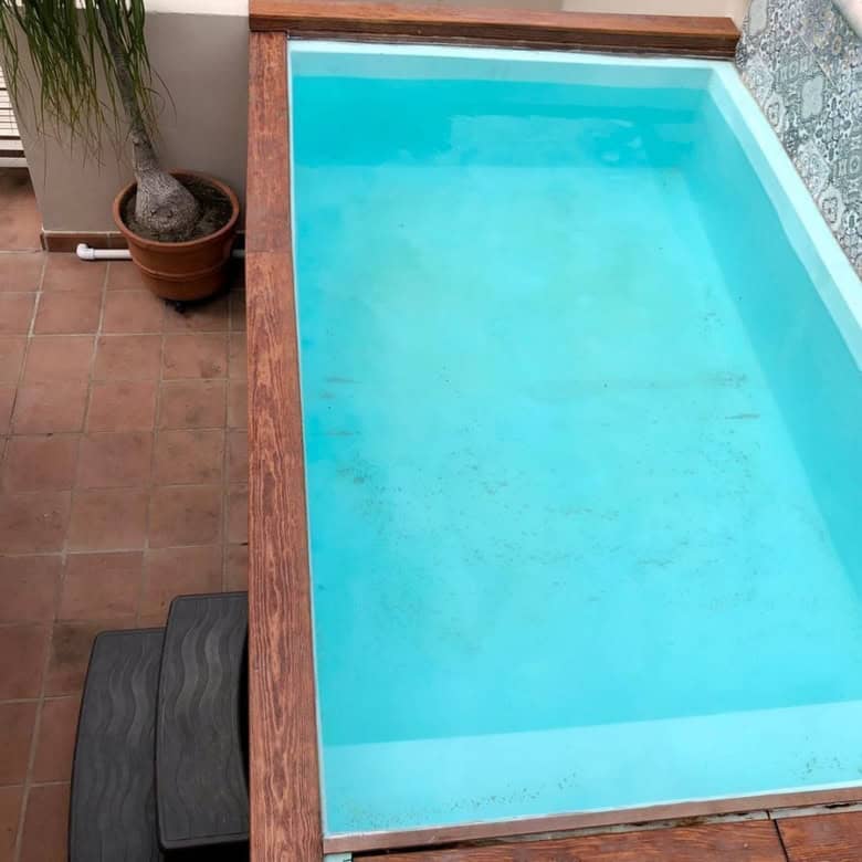 Modern private swimming pool with decorative wall tiles in a sunny outdoor space.