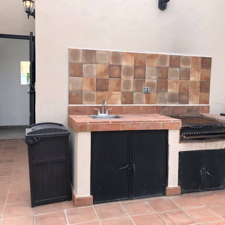Outdoor kitchen with sink and grill in a modern patio setting.