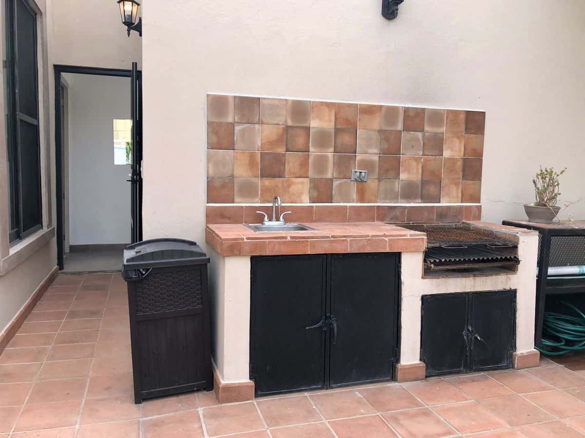 Outdoor kitchen with sink and grill in a modern patio setting.