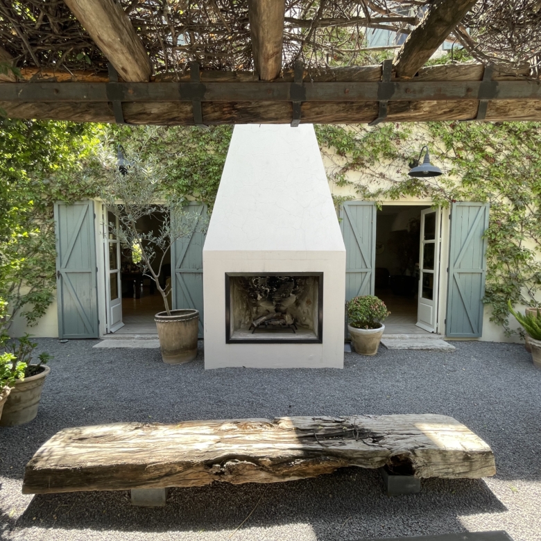 Charming outdoor fireplace with surrounding potted plants and garden seating.