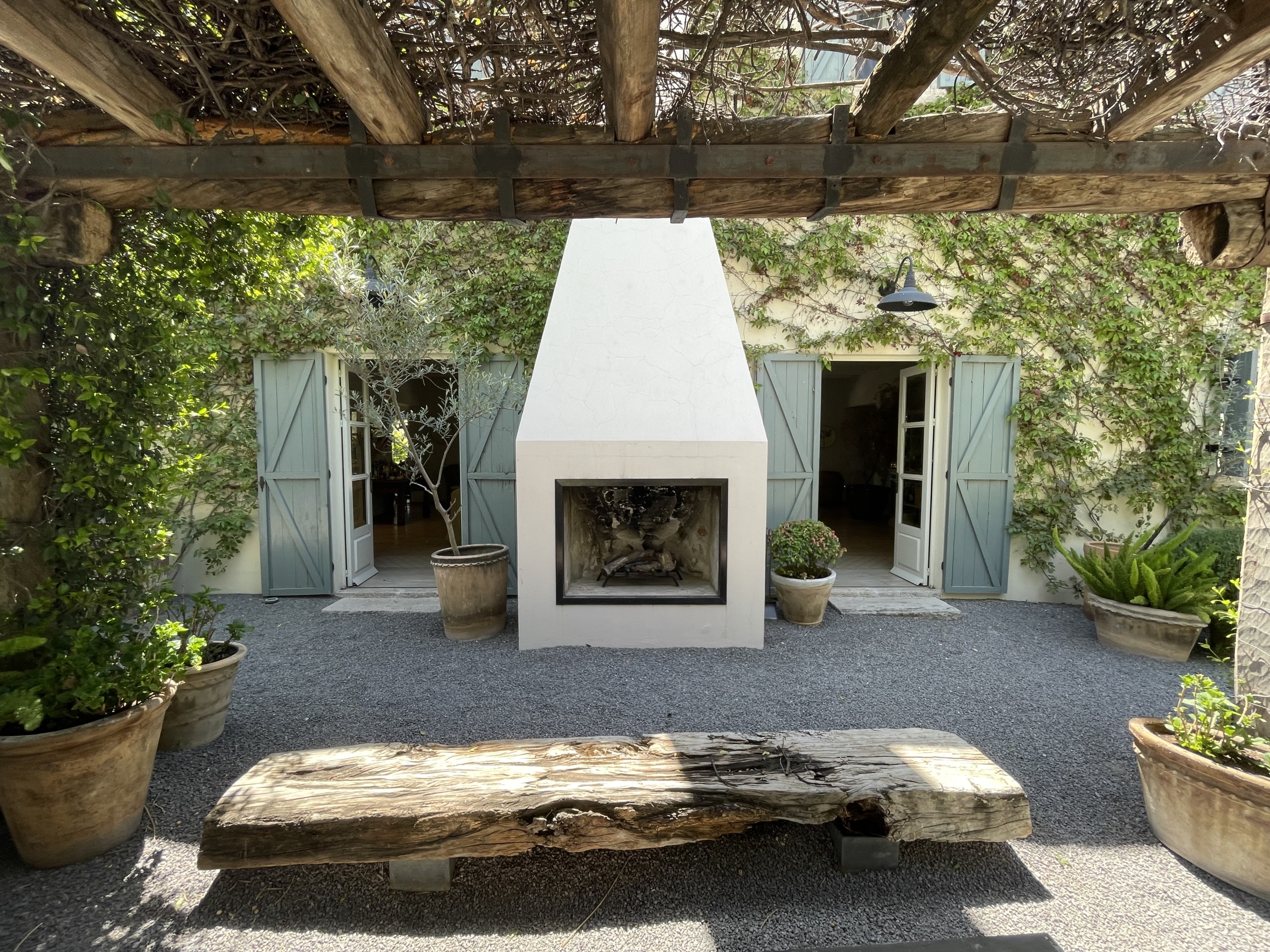 Charming outdoor fireplace with surrounding potted plants and garden seating.