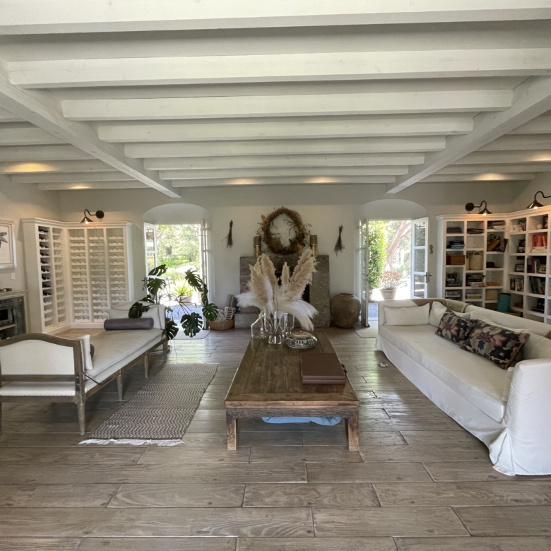 Bright and airy living room with white sofas, wooden flooring, and large windows for natural light.