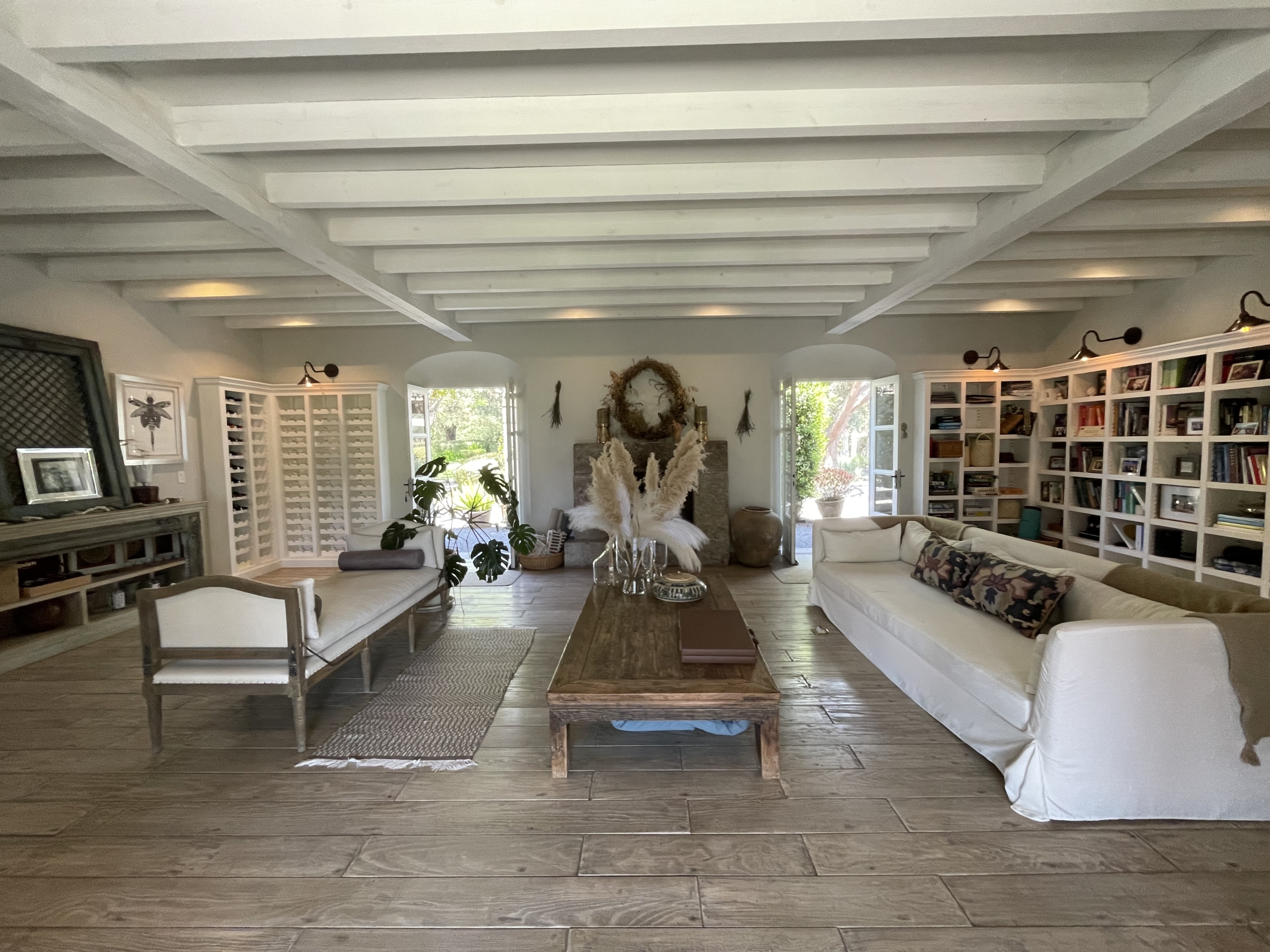 Bright and airy living room with white sofas, wooden flooring, and large windows for natural light.