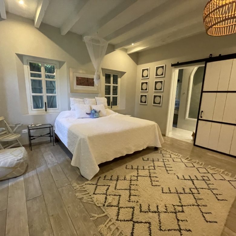 Spacious bedroom with white walls, wooden flooring, and stylish decor.