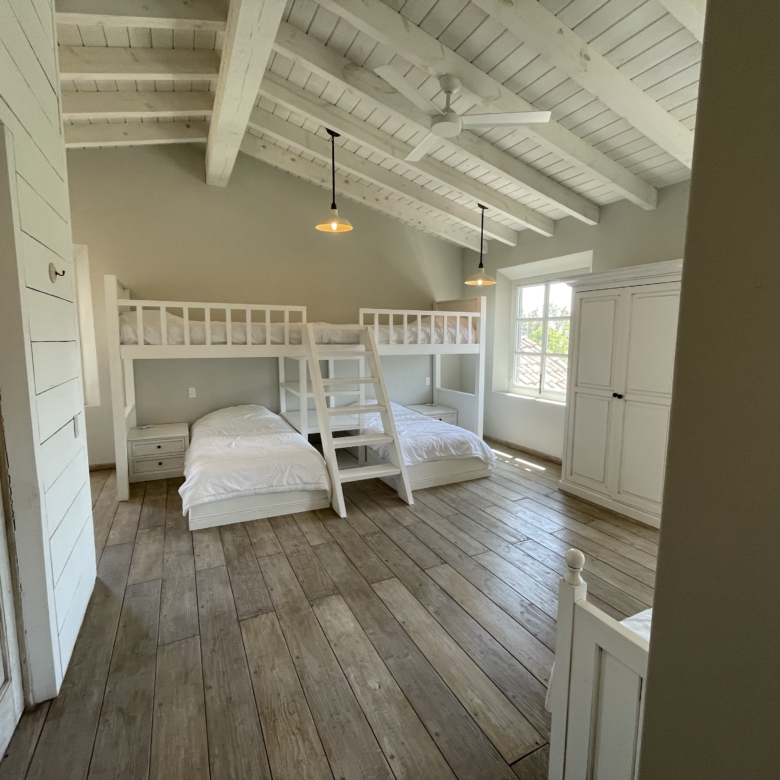 Bright bedroom featuring a white bunk bed and large window with natural light.