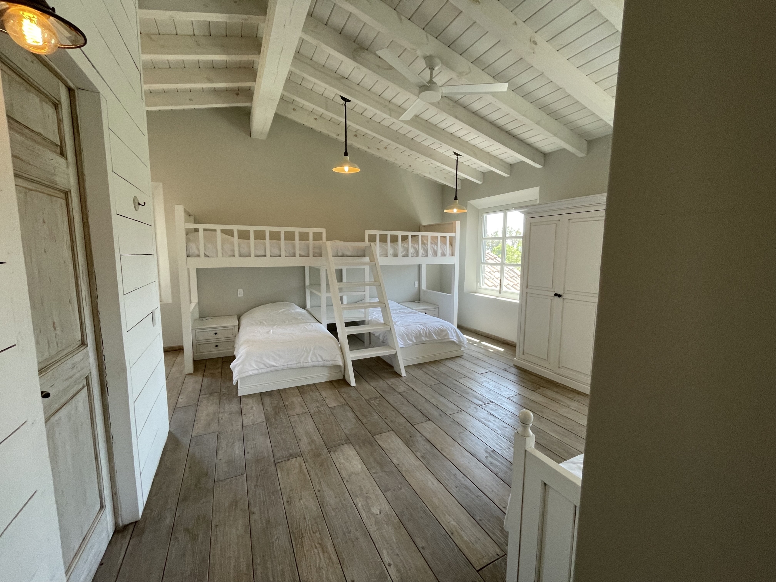 Bright bedroom featuring a white bunk bed and large window with natural light.