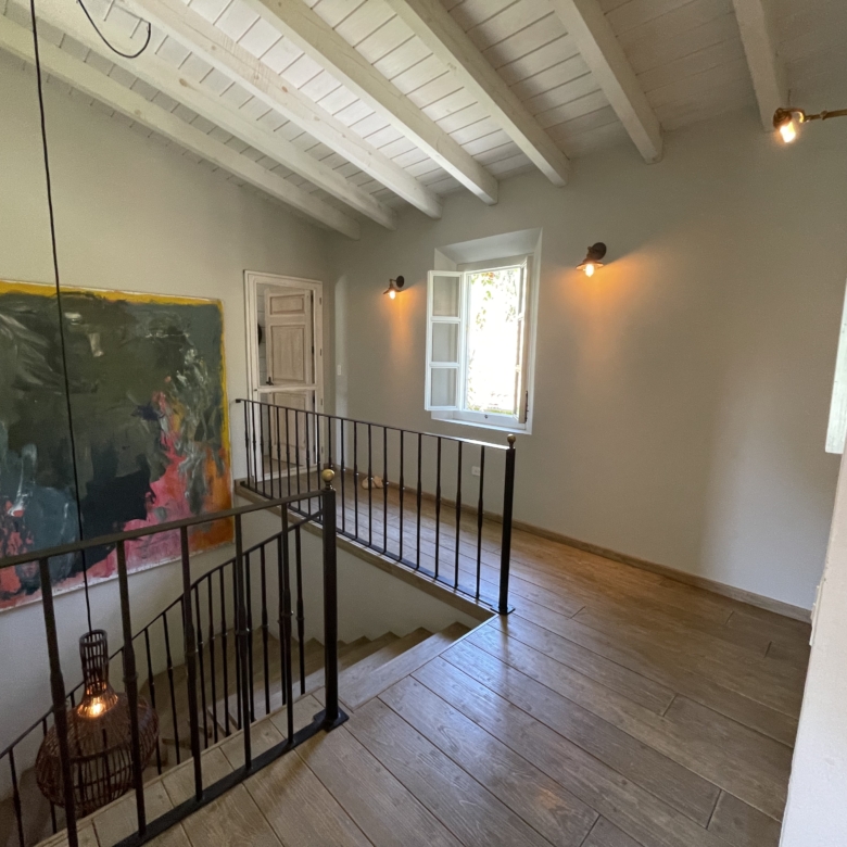 Interior of a stylish home with wooden floors, artwork, and natural light from windows.