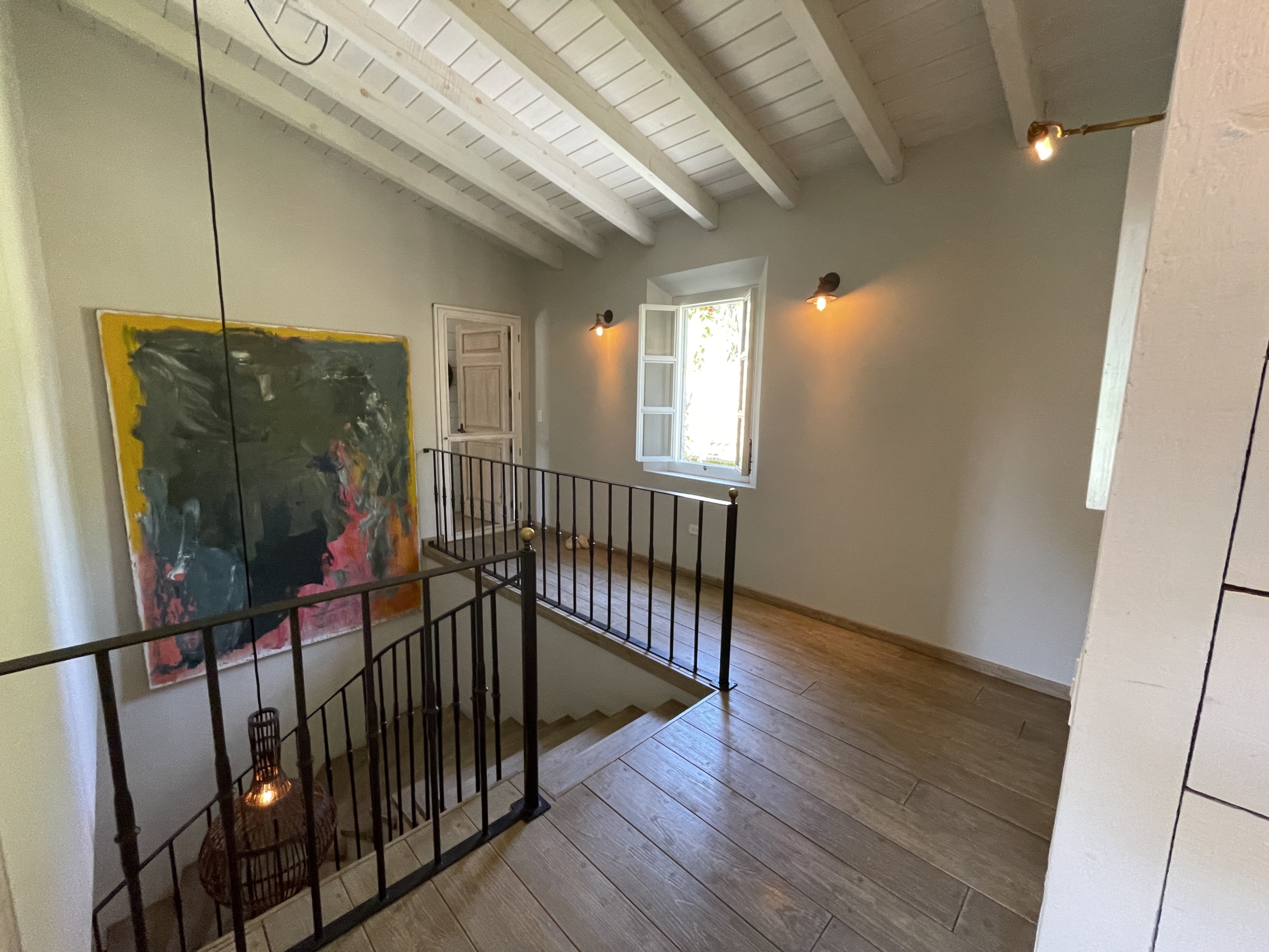 Interior of a stylish home with wooden floors, artwork, and natural light from windows.