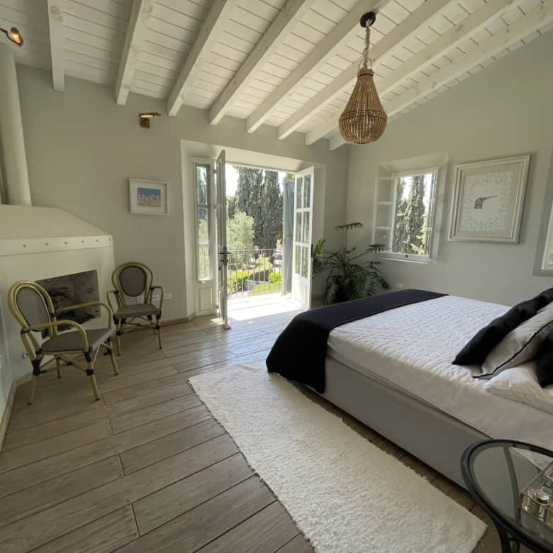 Bright bedroom with balcony, white walls, wooden floor, and natural light.