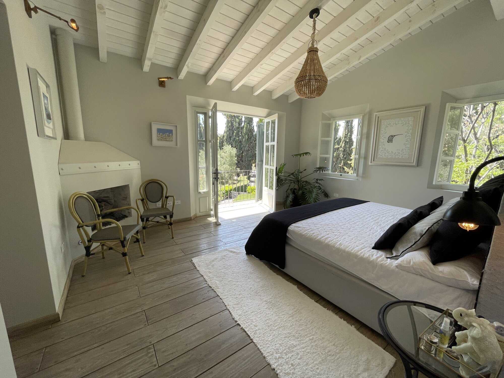 Bright bedroom with balcony, white walls, wooden floor, and natural light.