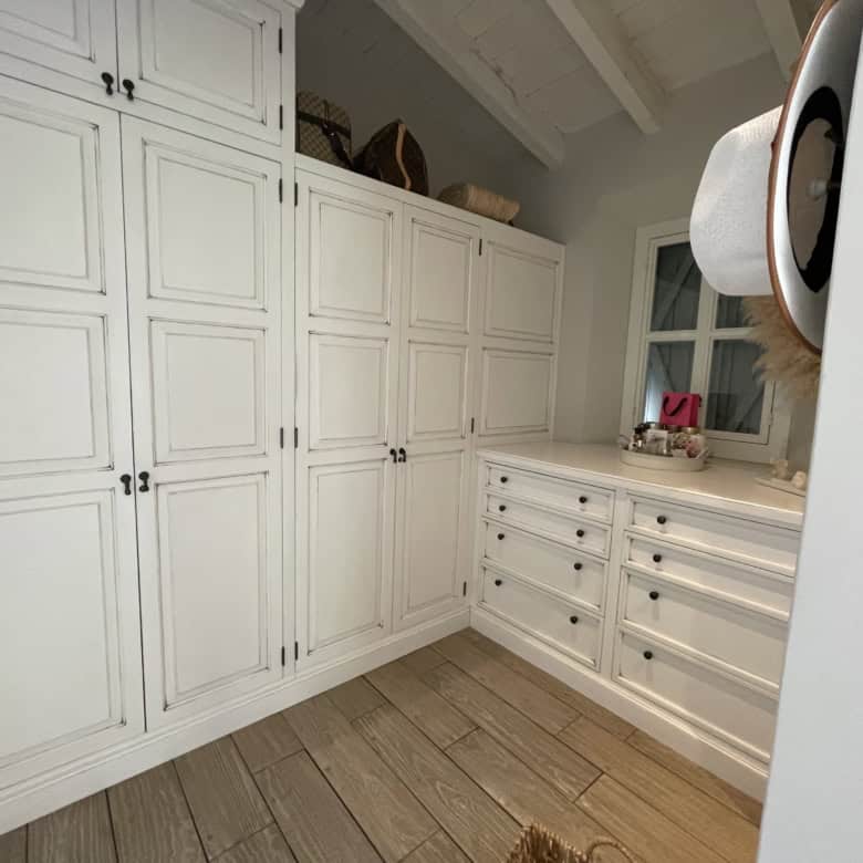 White built-in wardrobe and dresser with ample storage in a bright bedroom setting.