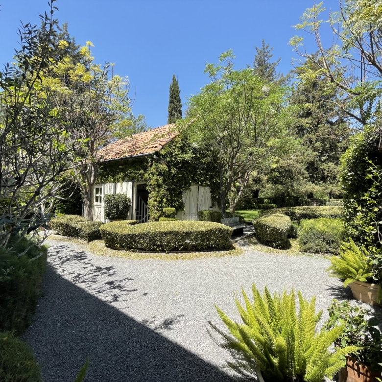 Beautiful garden scene with trees, shrubs, and a small house in a peaceful setting.