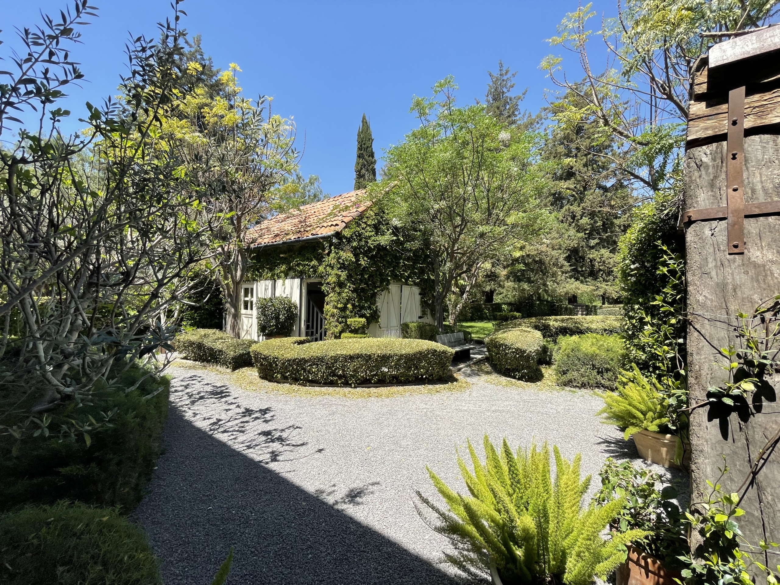 Beautiful garden scene with trees, shrubs, and a small house in a peaceful setting.