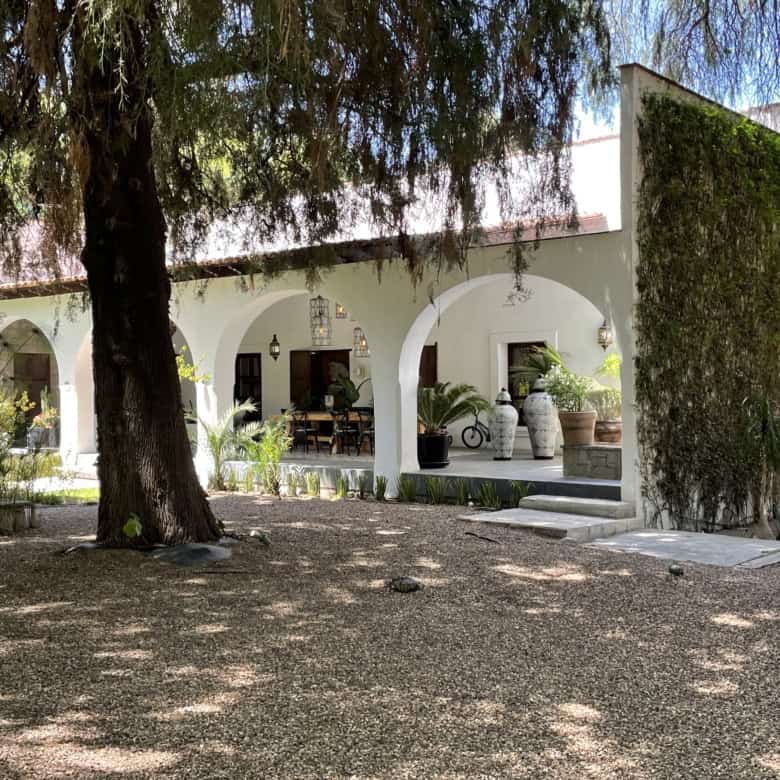 Beautiful Mediterranean villa with lush garden and shaded patio area.