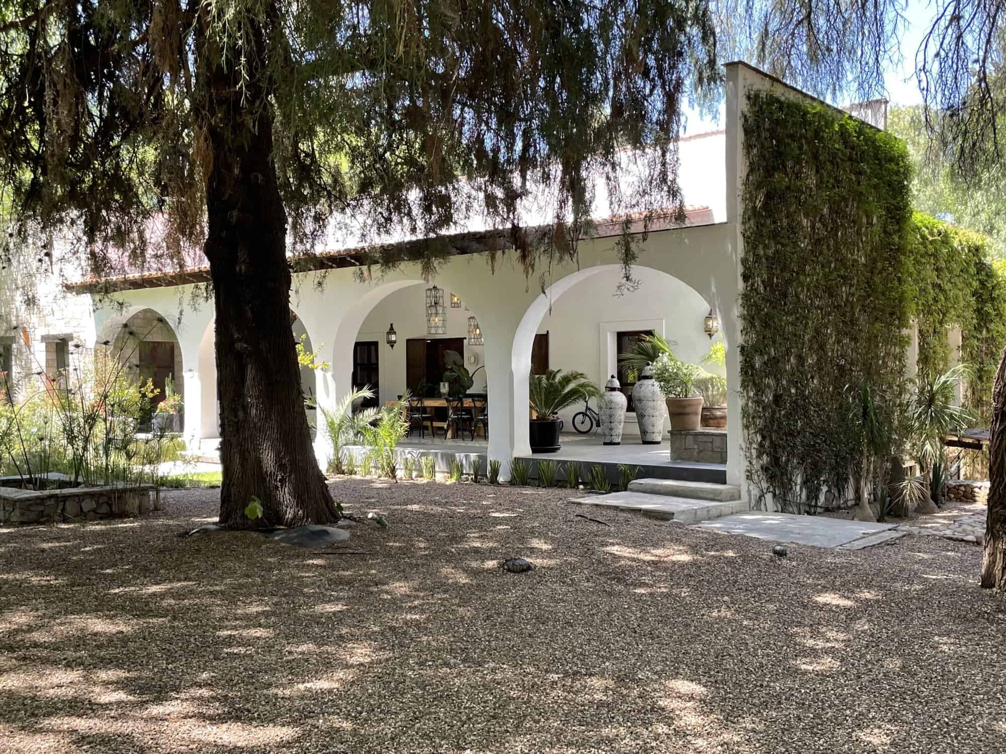 Beautiful Mediterranean villa with lush garden and shaded patio area.