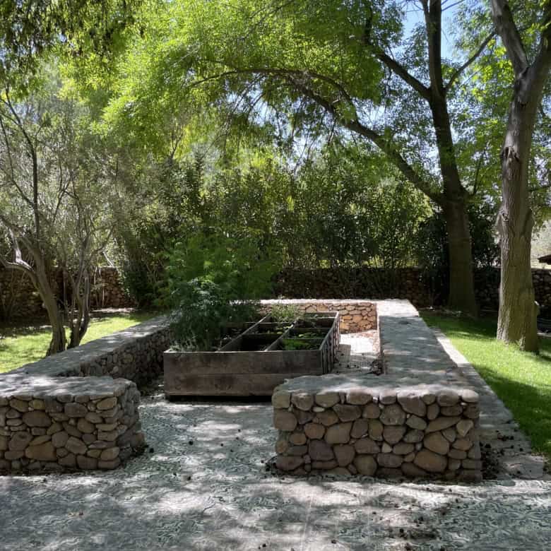 Garden with raised vegetable beds and lush trees in a peaceful outdoor setting.