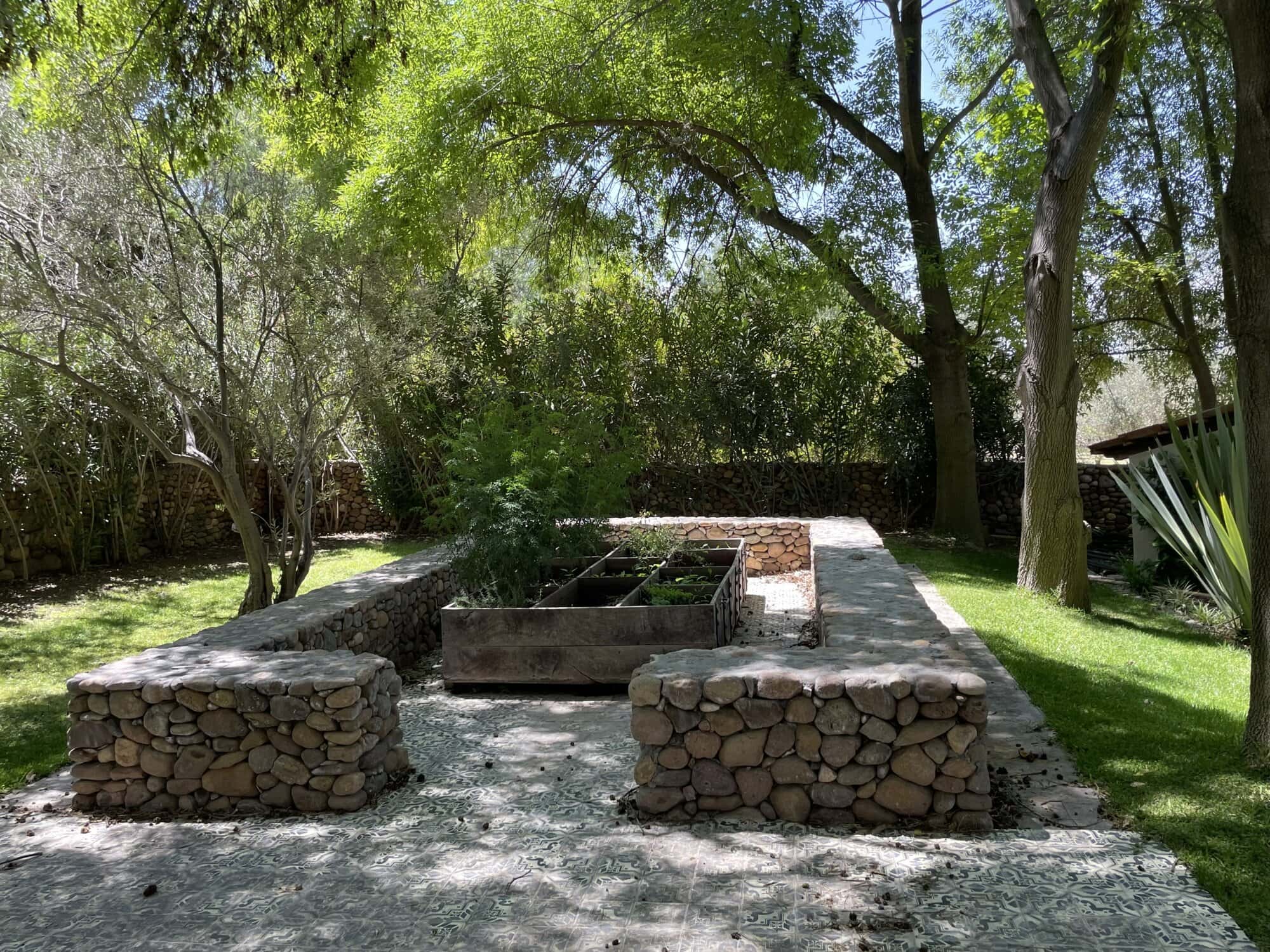 Garden with raised vegetable beds and lush trees in a peaceful outdoor setting.