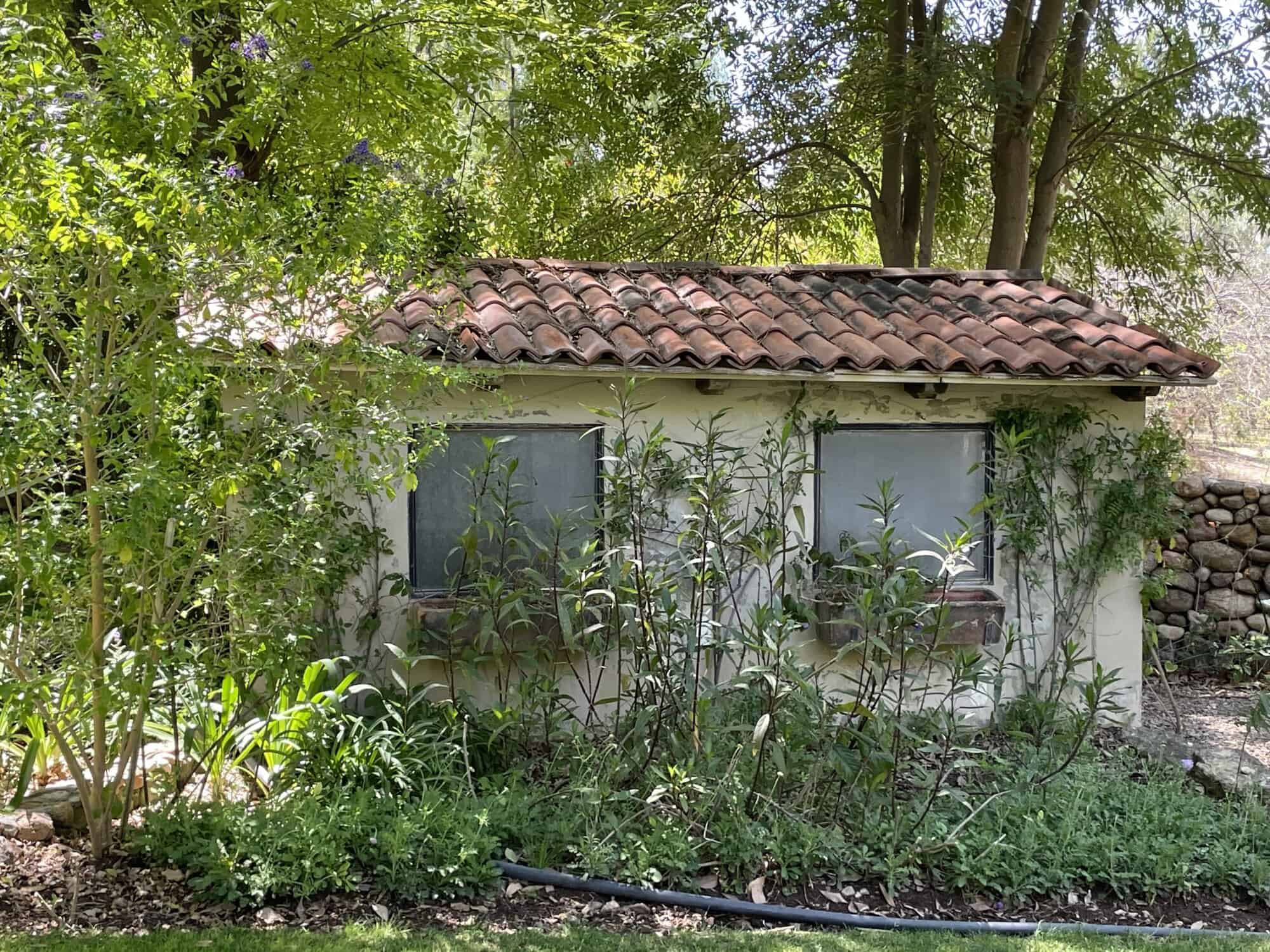 Cozy rural house surrounded by greenery, trees, and flowering plants, ideal for peaceful living or i.