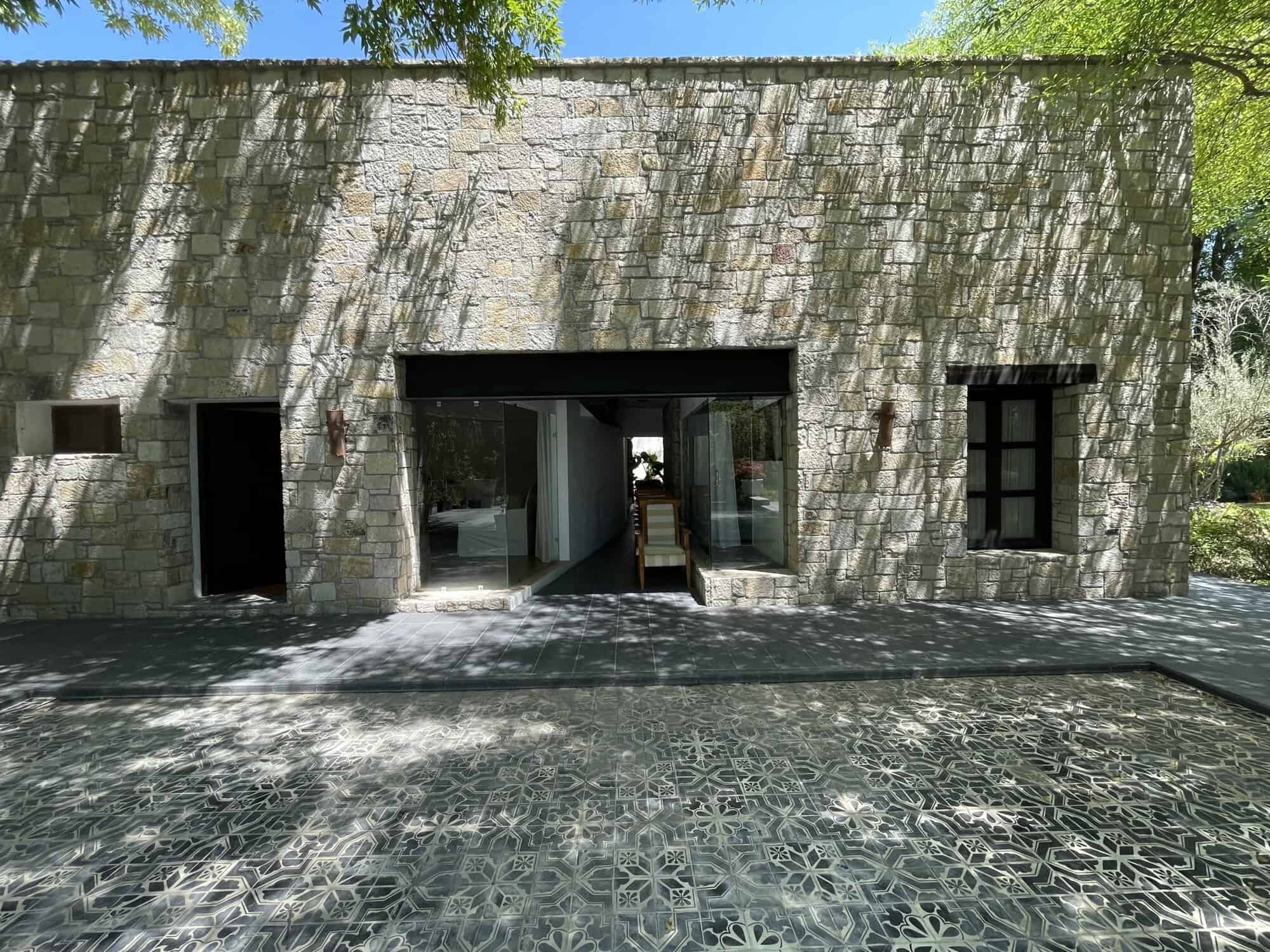 Modern stone villa with spacious entrance and garden views.