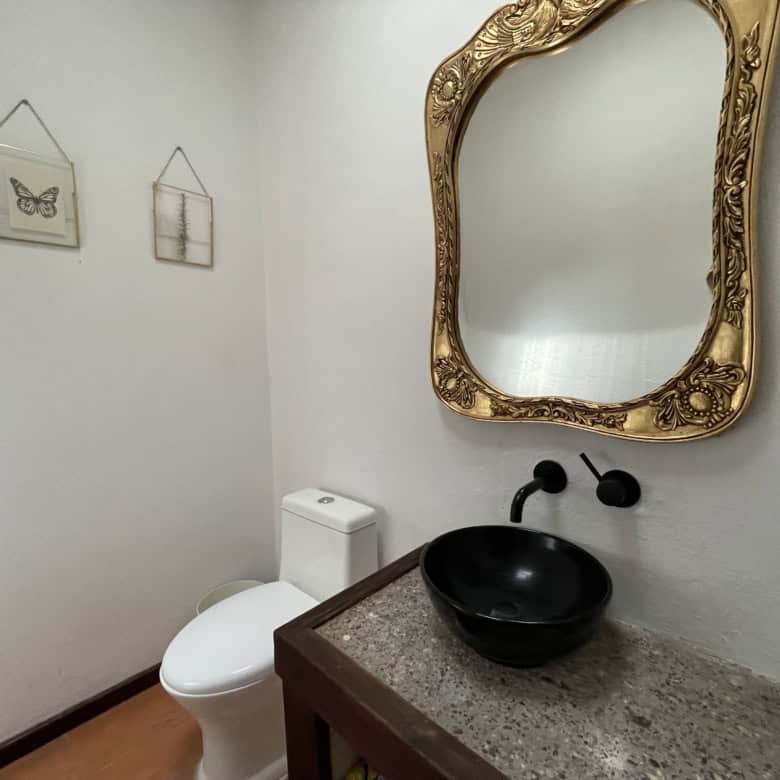 Modern bathroom featuring a black vessel sink and decorative mirror.