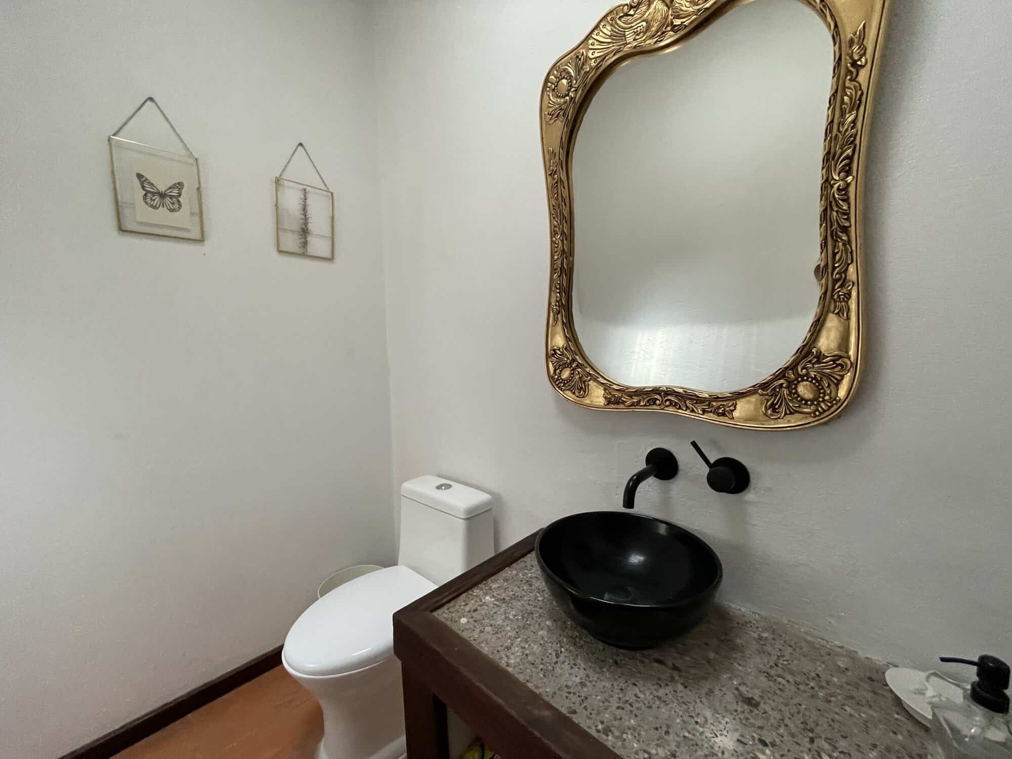 Modern bathroom featuring a black vessel sink and decorative mirror.